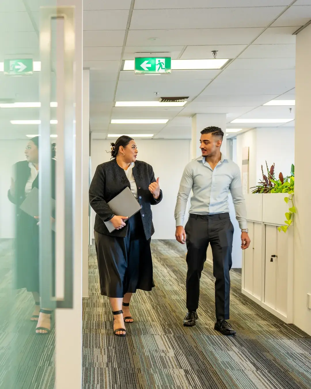 Two colleagues walking through a modern office discussing AI adoption