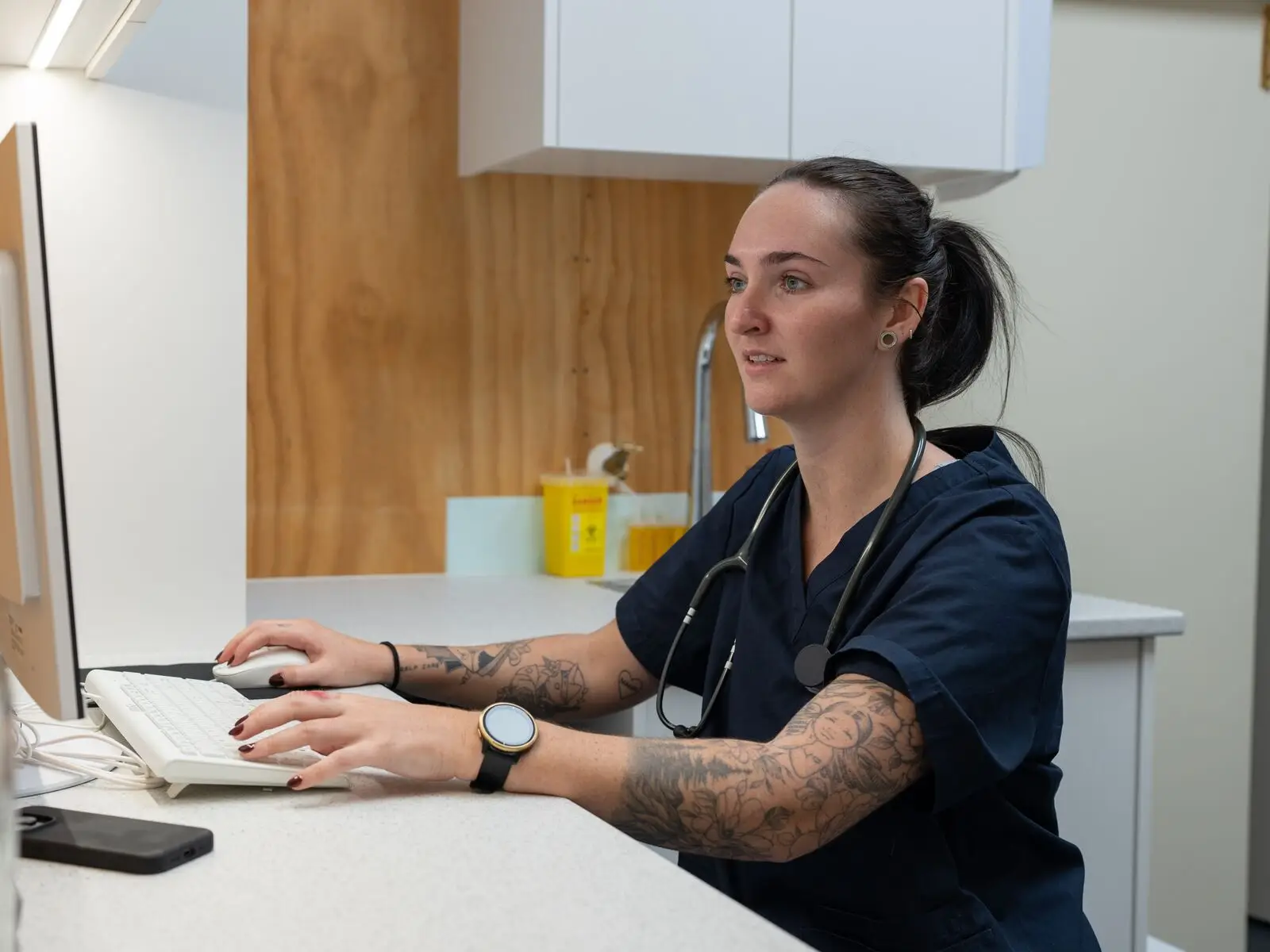 Health professional working at a computer in a New Zealand clinic